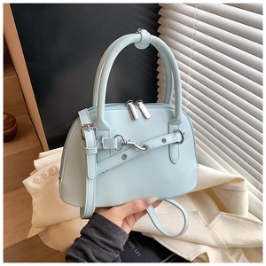 Detail of mint green shell handbag featuring double handles and silver dual-zipper closure