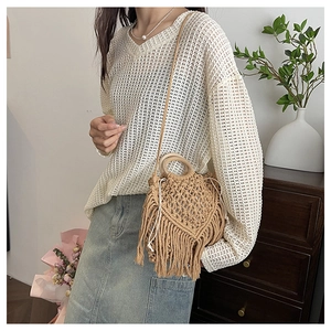 Detail of bohemian woven brown fiber handbag with tassels and round wooden handle