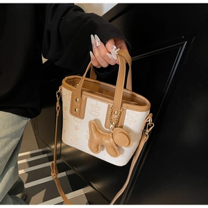 Détail du sac cabas monogramme blanc avec poignées marron et charm chien en cuir