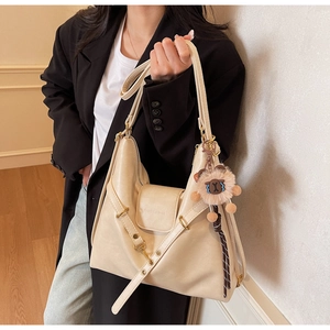 Detail view of cream hobo bag with gold buckle and a cute plush lamb pendant accessory