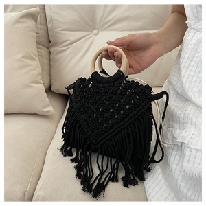 Detail of black woven rope tote bag with fringe tassels and circular wooden handles