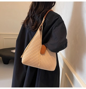 Detail of beige woven tote bag with V-shaped texture and rope shoulder strap