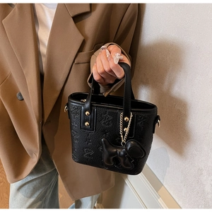 Détail du sac seau en cuir noir gaufré avec rivets dorés et joli pendentif chien