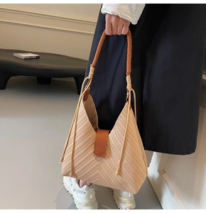 Detail of beige woven tote bag with V-shaped geometric texture and brown cord handle