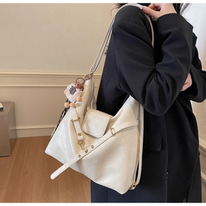 Detail of soft cream leather tote bag featuring chic embossed text and a plush charm