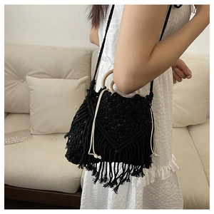 Detail of bohemian black woven bag with fringe, wooden handle and drawstring closure