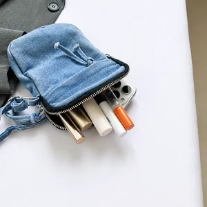 Internal view of a washed denim crossbody bag showing capacity for phone and lip glosses