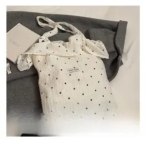 Detail of white ruffle mesh tote bag with black floral pattern and Magic pocket label