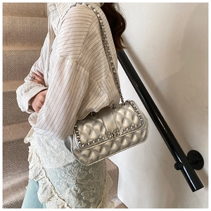 Detail of silver quilted crossbody bag with metallic finish and leather chain strap