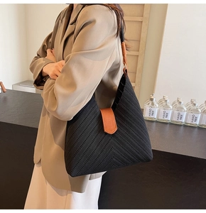 Detail of woven black hobo bag with brown leather strap and stylish V-shaped texture