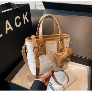Détails du logo gaufré et des finitions caramel sur le sac seau blanc crème