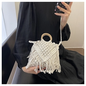 Detail of bohemian cream woven bag with long fringe tassels and round wooden handle