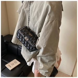Quilted black crossbody bag with silver chain strap worn with casual outfit style
