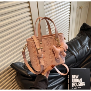 Détail du sac seau rose gaufré avec motifs d'étoiles et un charmant pendentif chien