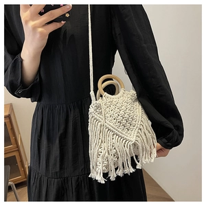 Detail of bohemian woven bag with white cotton rope fringe and round wooden handles