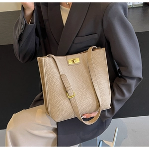 Close-up of beige lychee texture bucket bag with adjustable strap and gold metal buckle