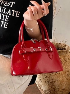 Chic red patent leather shell handbag with glossy finish and silver eyelet strap detail