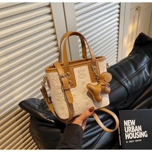 Détail du sac seau crème et marron avec motifs d'étoiles et breloque petit pain d'épices