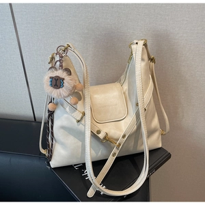 Detail of soft off-white faux leather tote with adjustable straps and plush bear charm