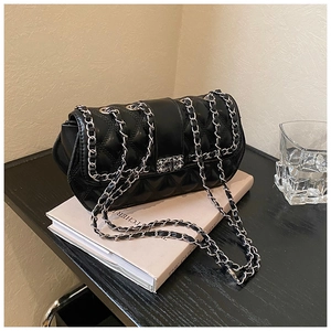 Detail of black quilted leather shoulder bag with silver chain strap and metal lock closure