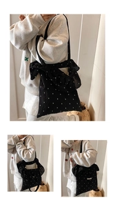 Detailed view of black floral canvas tote bag featuring a large decorative side bow