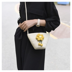 Detail of a handmade cream crochet bucket bag featuring yellow flowers and rope strap