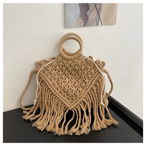 Detail of bohemian macrame woven bag with wooden ring handles and long fringe tassels