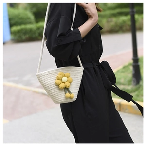 Detail of a handmade off-white woven bucket bag with a yellow 3D knitted flower decoration