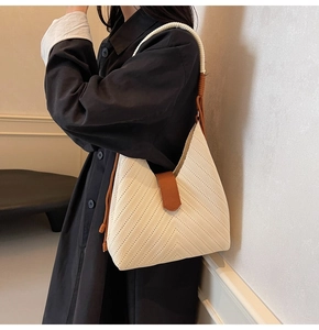 Close-up of the woven knit texture and brown leather strap detail on this tote bag