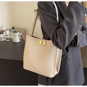 Detail of minimalist beige pebble leather bucket bag with a golden twist lock closure