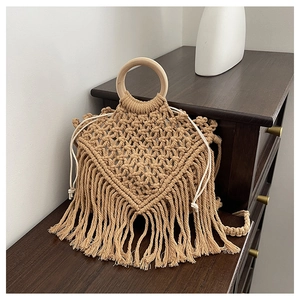 Detail of bohemian hand-woven macrame bag with wooden handle, fringes and drawstring