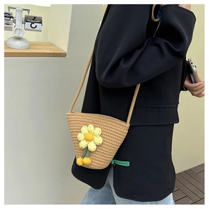 Detail of hand-woven straw bucket bag with crochet sunflower and cherry decorations