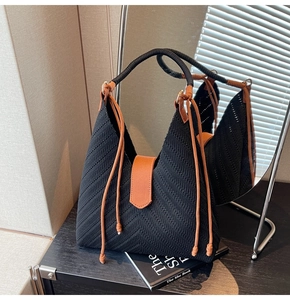 Detail of woven tote bag featuring black wave texture and brown leather straps