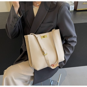 Chic beige lychee leather bucket bag styled with a professional grey business suit