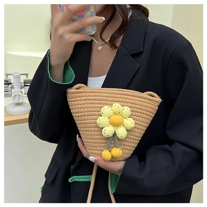Detail of a straw woven bucket bag with handmade yellow crochet flower decoration