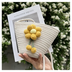 Close-up of a cream woven bucket bag featuring large yellow floral accents and soft tassels