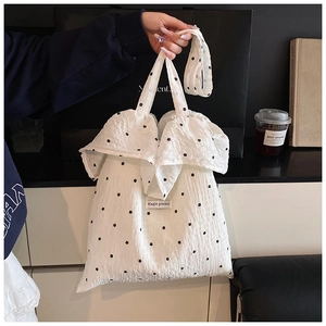 Detailed texture of ruffled chiffon tote bag with black floral pattern and woven label
