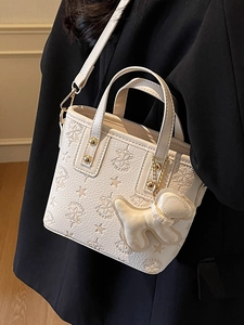 Sac seau beige chic gaufré avec motif d'étoiles et charm cœur sur blazer noir