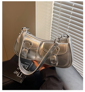 Close-up of metallic silver Y2K underarm bag featuring double buckle pockets and wide strap