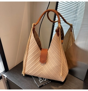 Detailed knit texture of a beige woven tote bag with brown straps on a dark table