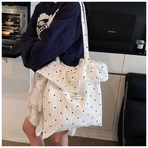 Detail showing white ruffled chiffon tote bag with black star patterns and Magic Pocket label