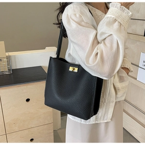 Detailed close-up of black lychee grain leather tote bag with elegant gold metal lock