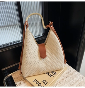 Close-up of cream woven tote bag featuring V-shaped texture and brown leather clasp detail