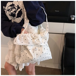 Close-up of white ruffle tote bag with black floral print and Magic Pocket label