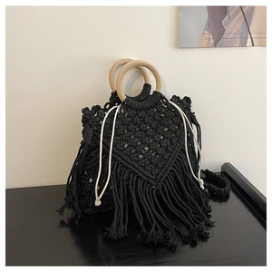 Close-up of black macrame weave bag with long tassels and round wooden handles