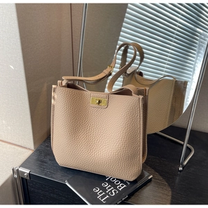Detail of lychee pattern leather bucket bag with gold twist lock and adjustable strap