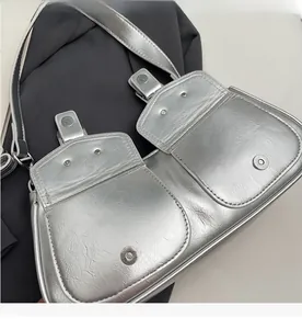 Detail shot of strong magnetic buckles and dual pockets on silver metallic shoulder bag