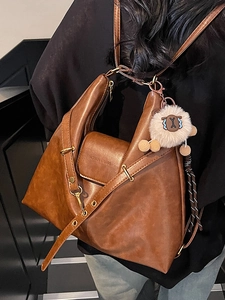 Brown leather tote bag with geometric folding design and white sheep plush keychain