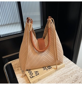 Close-up of beige chevron knit tote bag with thick woven rope handles on marble