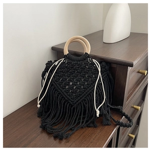 Detail of hand-woven black rope tote bag with round wooden handles and long fringe decor
